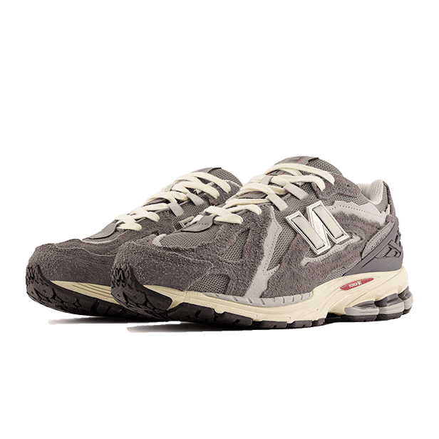 Grey and beige New Balance 1906D Protection Pack Castlerock sneakers on a green background