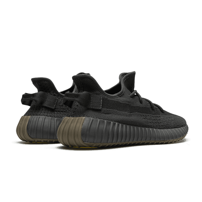 Zwarte Adidas Yeezy Boost 350 V2 Cinder (niet reflecterend) sneakers op een donkergroene achtergrond