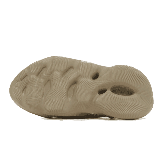 Adidas Yeezy Foam RNR Stone Salt - kenmerkende schuimrubber zool met golflijn textuur op een groene achtergrond