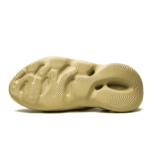 Comfortabele Adidas Yeezy Foam RNR Sulfur sneakers met organische, afgeronde vormen op een lichtgele zool getoond op een donkergroene achtergrond.