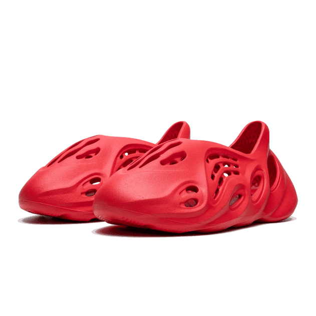 Rode Adidas Yeezy Foam RNR sneakers op een groene achtergrond