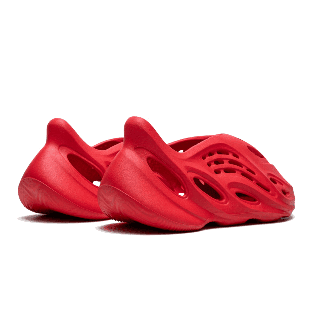 Rode Adidas Yeezy Foam RNR sneakers op een groene achtergrond