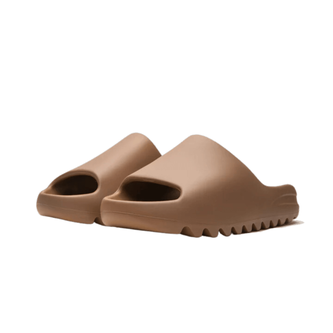 Stijlvolle Adidas Yeezy Slide Core slippers op strakke groene achtergrond - ultieme comfort voor de moderne stedeling.