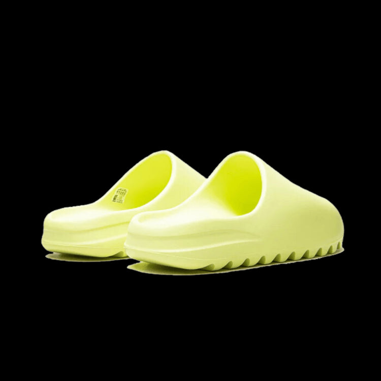 Gele Adidas Yeezy Slide Glow Green (Restock Pair 2022) sneakers tegen een groene achtergrond