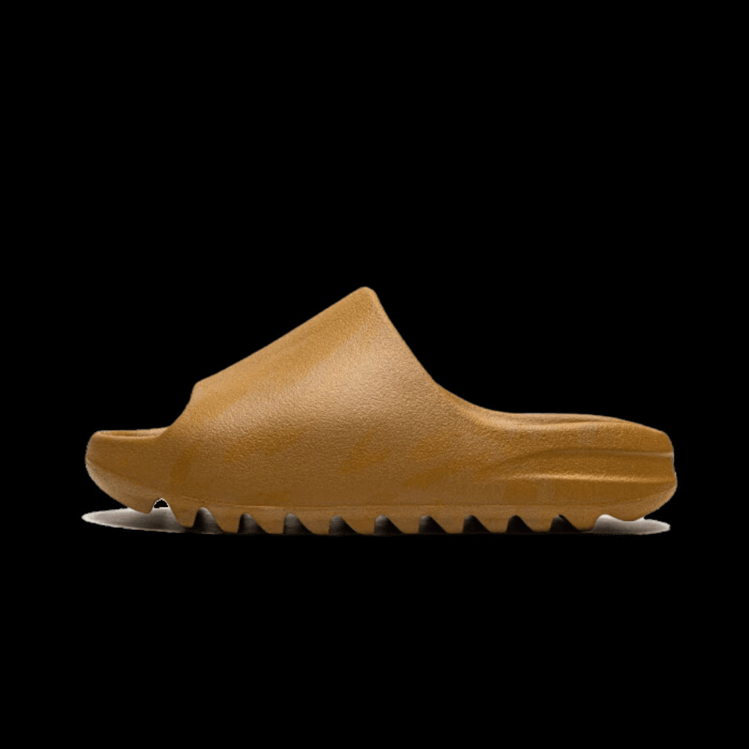 Bruine Adidas Yeezy Slide Ochre-sandalen op een groene achtergrond