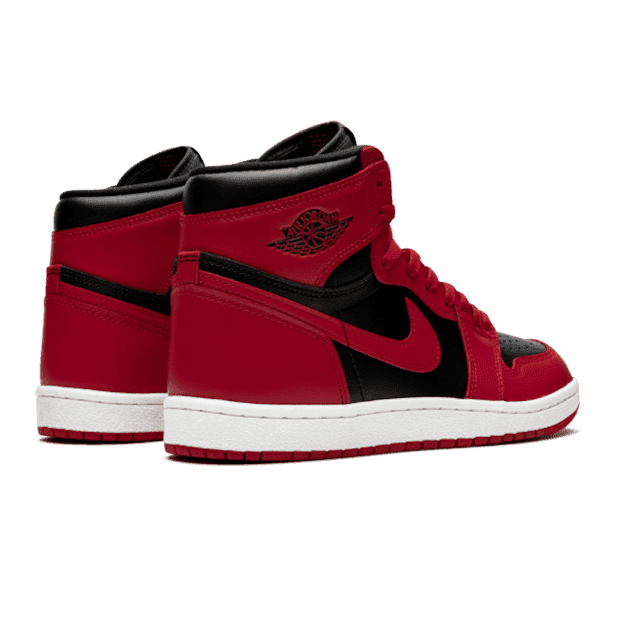 Stoere Air Jordan 1 High 85 Varsity Red sneakers op een groene ondergrond. Deze iconische basketbalschoenen hebben een rood leren bovenwerk, zwarte details en het klassieke Jumpman-logo. Deze exclusieve sneakers zijn de ultieme keuze voor wie stijlvol uit de hoek wil komen.