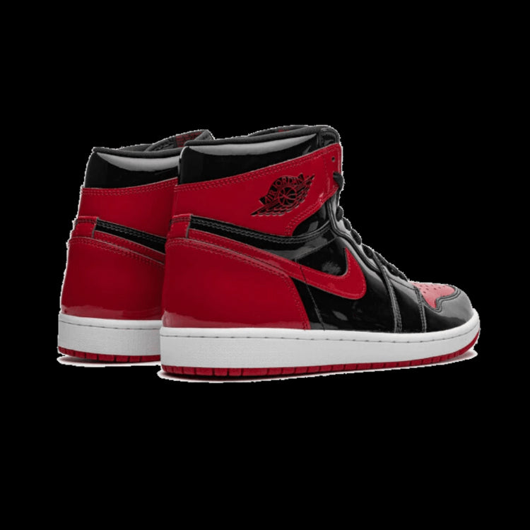 Rode en zwarte Air Jordan 1 High OG Patent Bred sneakers op groene achtergrond. Exclusieve en iconische basketbal-schoen met kenmerkende Nike-swoosh en Air Jordan-logo.