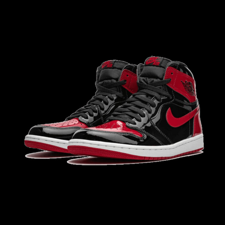 Zwarte en rode Air Jordan 1 High OG Patent Bred sneakers op een groene achtergrond