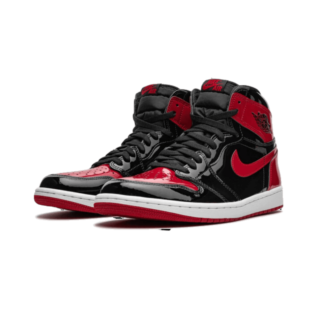 Zwarte en rode Air Jordan 1 High OG Patent Bred sneakers op een groene achtergrond