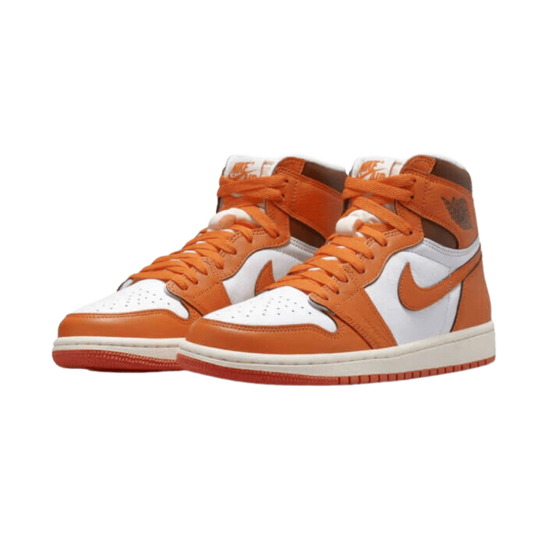 Oranje en witte Air Jordan 1 High OG Starfish sneakers op een groene achtergrond