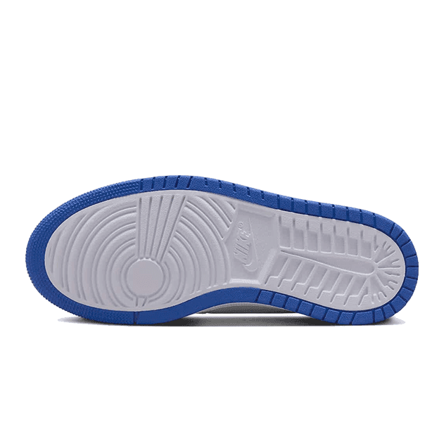 Blauwe en grijze Nike Air Jordan 1 High Zoom Air CMFT sneaker met een opvallende zoolconstructie op een groene achtergrond.