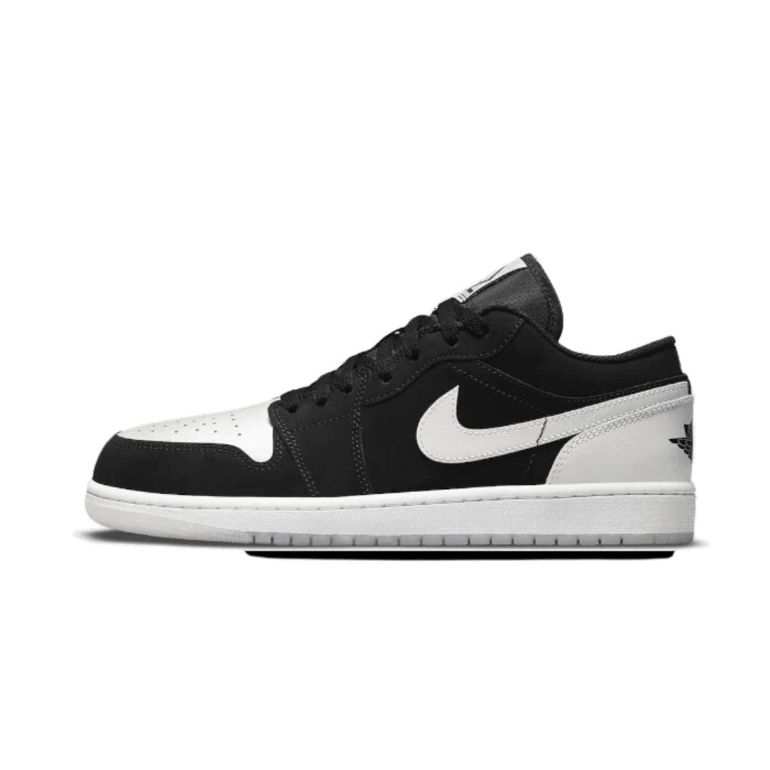 Elegante Nike Air Jordan 1 Low Black White Diamond sneakers op een groene achtergrond. Deze klassieke lage sneakers combineren zwarte en witte accenten voor een stijlvolle look.