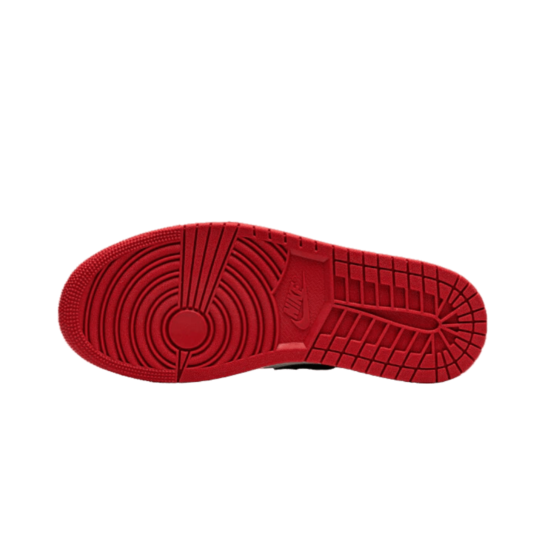 Rode Air Jordan 1 Low Bred Toe (2021) sneakers op een groene achtergrond