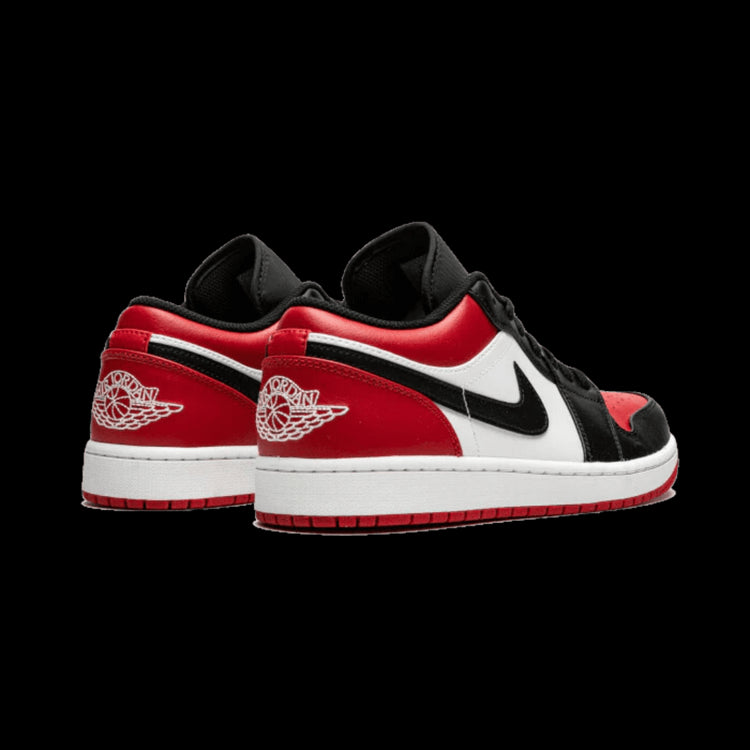 Air Jordan 1 Low Bred Toe (2021) sneakers op een effen groene achtergrond. Deze rode en zwarte sneakers hebben witte elementen en zijn gemaakt door het merk Nike. Een klassieke en stijlvolle sneaker uit de populaire Air Jordan-lijn.