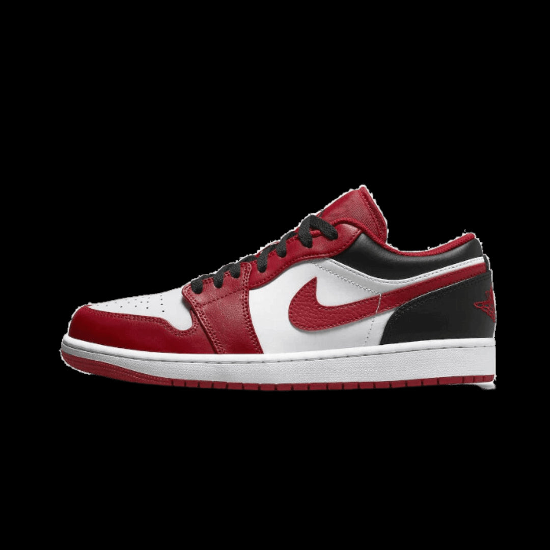 Rode, zwarte en witte Nike Air Jordan 1 Low Bulls sneakers, getoond tegen een groene achtergrond.