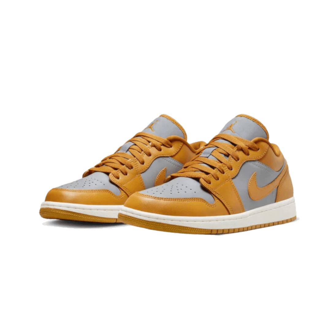 Oranje Nike Air Jordan 1 Low sneakers met cement grijze accenten op een groene achtergrond
