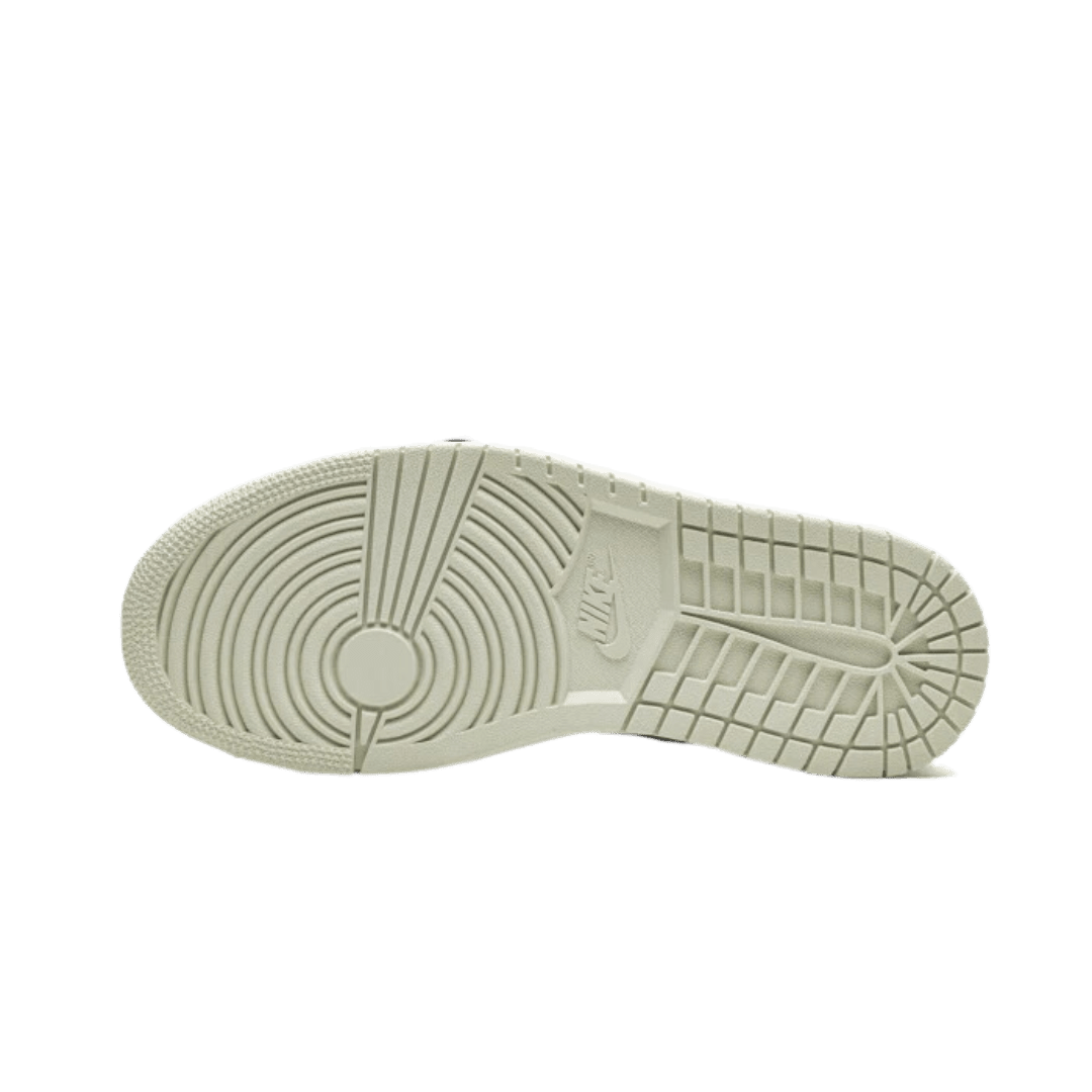 Witte, klassieke Nike Air Jordan 1 Low Coconut Milk sneakers met een rubberen zool op een groene achtergrond.