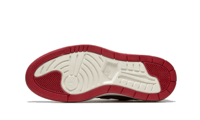 Rode en witte Air Jordan 1 Low Elevate sneakers met een opvallend geprofileerde zool op een groene achtergrond.