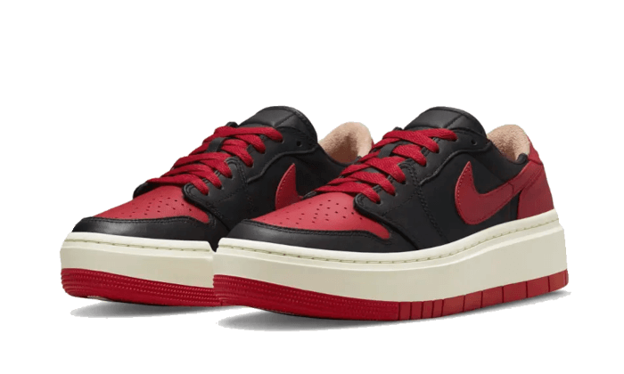 Zwarte en rode Nike Air Jordan 1 Low Elevate sneakers op een groene achtergrond. Deze klassieke sneakers hebben een lederen bovenwerk met een zool met rode accenten.