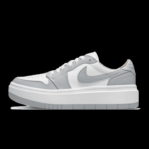 Witte en grijze Nike Air Jordan 1 Low Elevate sneakers geplaatst op een groene achtergrond