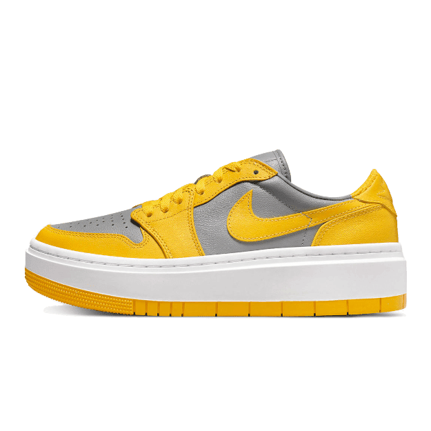 Grijze en gele Nike Air Jordan 1 Low Elevate sneakers op een groene achtergrond in het beeld.