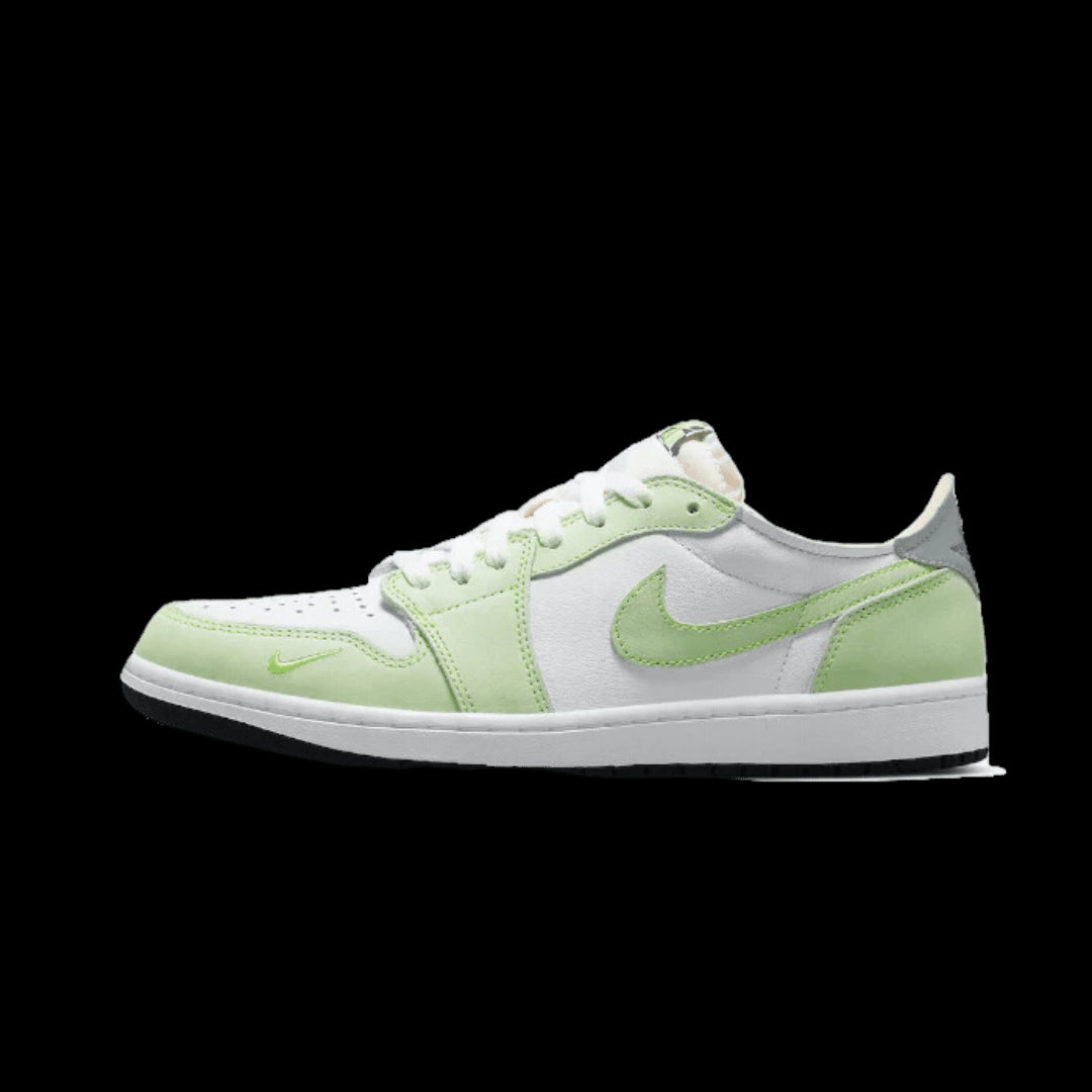 Klassieke witte en lichtgroene Nike Air Jordan 1 Low OG sneakers op een effen groene achtergrond. De sneakers hebben een stijlvolle en moderne look met de kenmerkende Nike swoosh branding op de zijkant. Deze stijlvolle schoenen zijn ideaal voor een casual en comfortabele dagelijkse look.