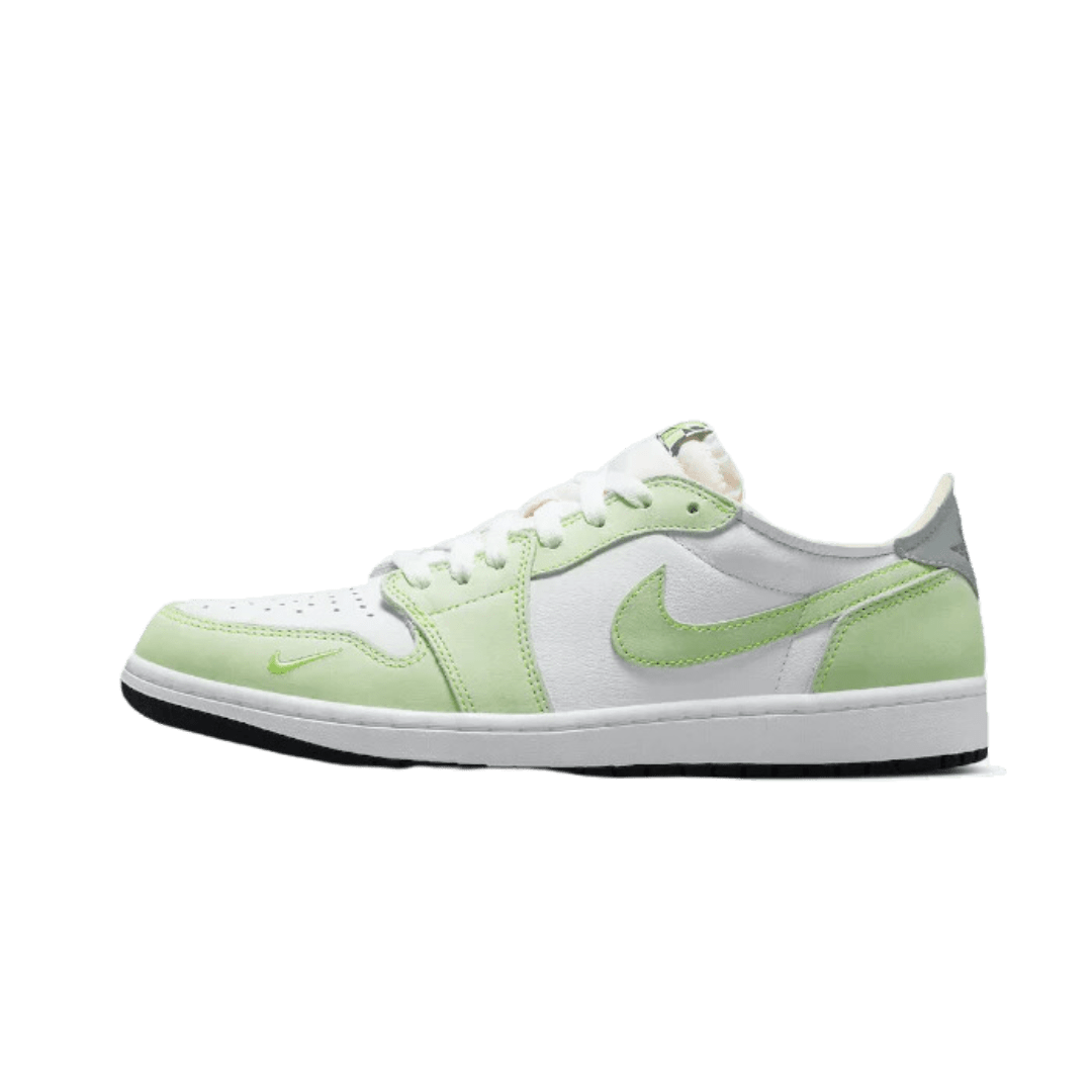 Klassieke witte en lichtgroene Nike Air Jordan 1 Low OG sneakers op een effen groene achtergrond. De sneakers hebben een stijlvolle en moderne look met de kenmerkende Nike swoosh branding op de zijkant. Deze stijlvolle schoenen zijn ideaal voor een casual en comfortabele dagelijkse look.