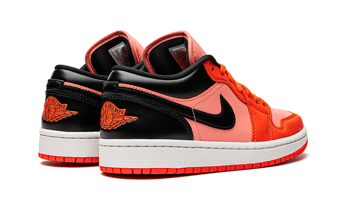 Oranje en zwarte Nike Air Jordan 1 Low sneakers met kenmerkende Jordan-vleugels op de zijkant.