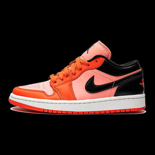 Oranje en zwarte Nike Air Jordan 1 Low sneakers tegen een groene achtergrond