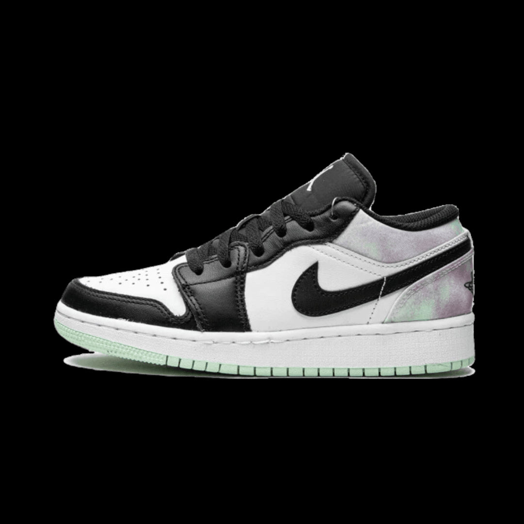 Pastel gekleurde Nike Air Jordan 1 Low sneakers met zwart-wit details op een groen oppervlak geplaatst.
