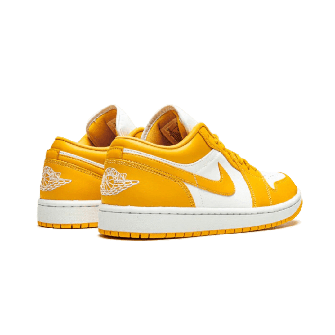 Gele lage sneakers van Nike, de Air Jordan 1 Low Pollen, met het kenmerkende Swoosh-logo op de zijkant en een stijlvolle witte zool.