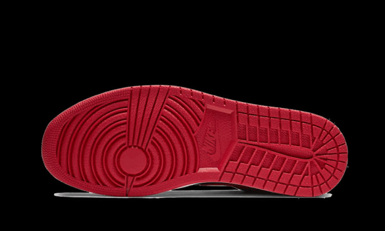 Elegante Air Jordan 1 Low Reverse Bred sneakers met een opvallende rode zool en gestroomlijnde vormgeving op een groene achtergrond.