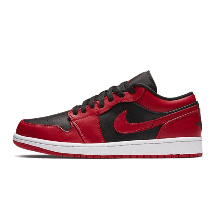 Rode en zwarte Nike Air Jordan 1 Low Reverse Bred sneakers tegen een groene achtergrond