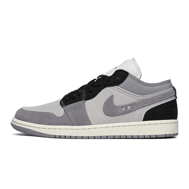 Grijze Air Jordan 1 Low SE Craft sneakers op een groene achtergrond. De sneakers hebben een grijze kleur met zwarte accenten en een klassiek Nike-logo op de zijkant. Het is een modieus lage sneakermodel met een rubberen zool voor optimaal comfort.