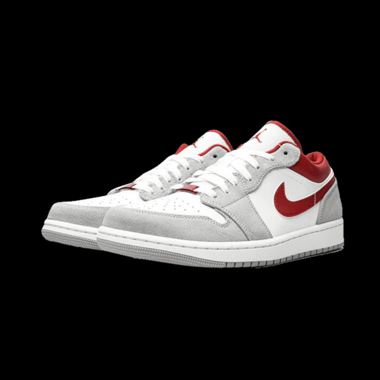 Witte en rode Nike Air Jordan 1 Low SE sneakers op een groene achtergrond