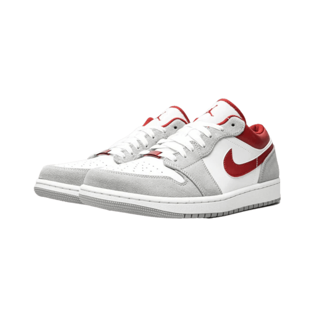 Witte en rode Nike Air Jordan 1 Low SE sneakers op een groene achtergrond
