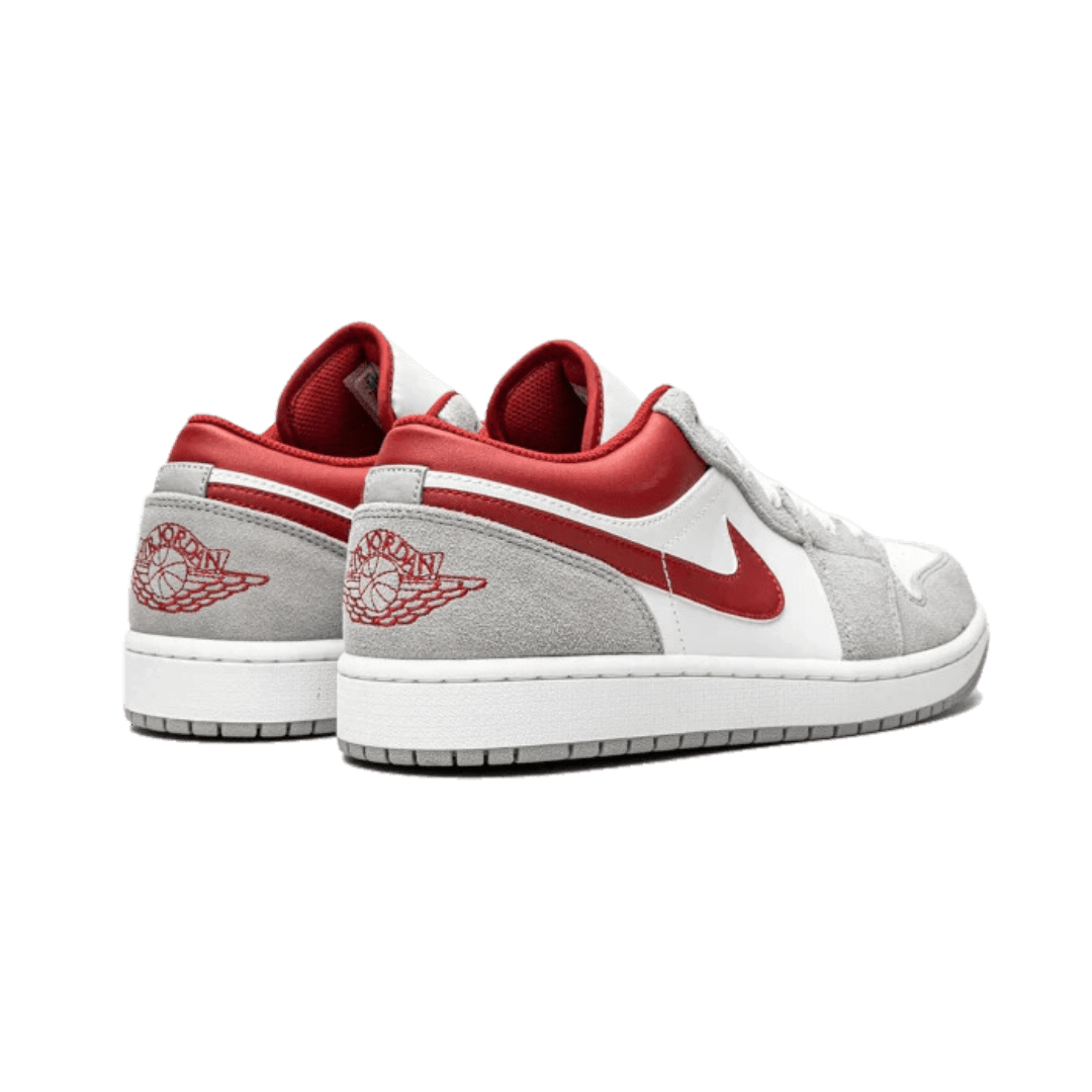 Rode en grijze Air Jordan 1 Low SE sneakers op een groene achtergrond
