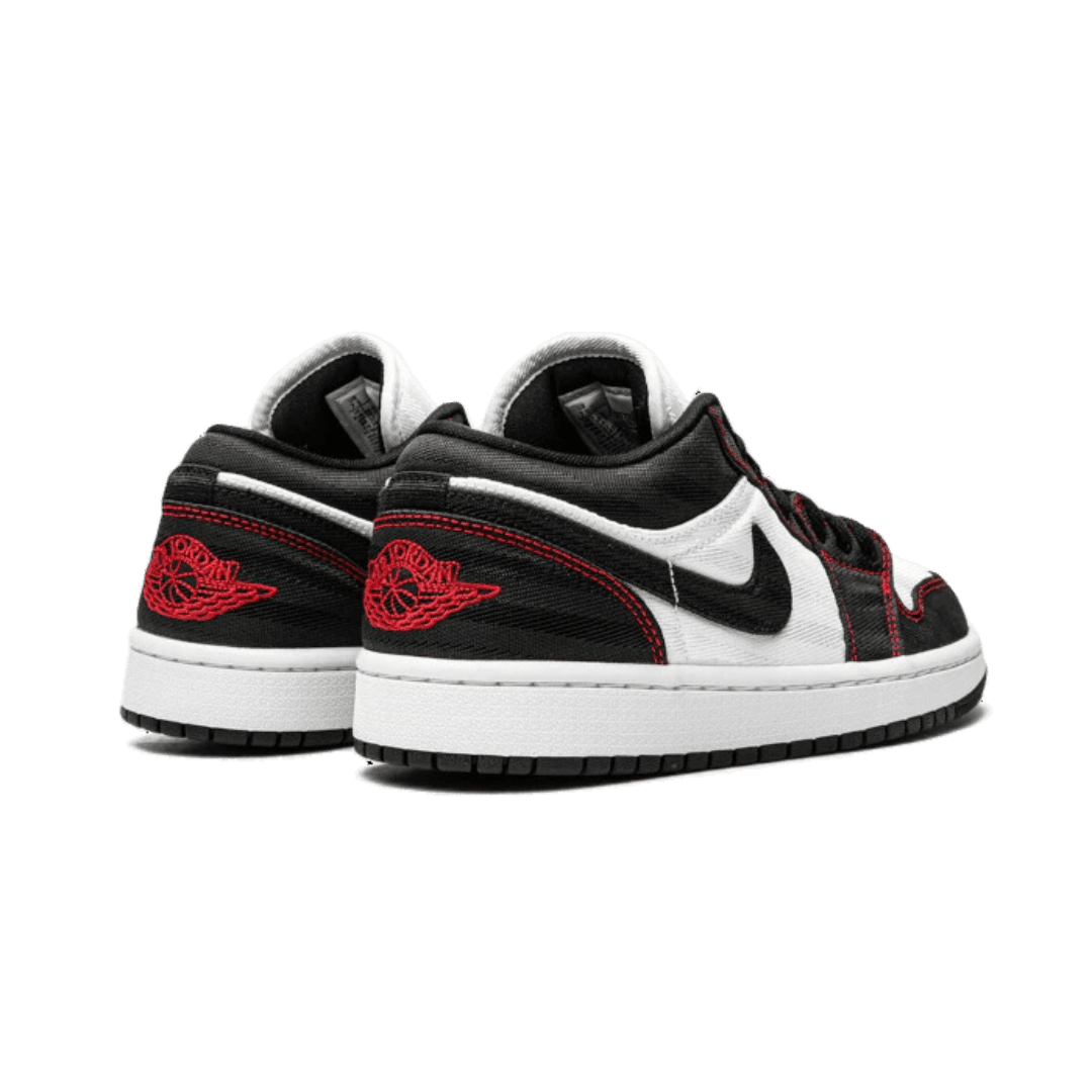 Zwarte en witte Nike Air Jordan 1 Low SE Utility sneakers met rode details op een groene achtergrond
