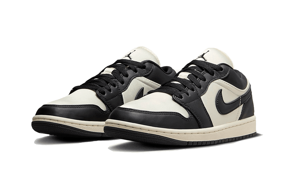 Klassieke Air Jordan 1 Low SE Vintage Panda sneakers in zwart-wit, geplaatst op een groen oppervlak. Deze Nike-sneakers kenmerken zich door hun elegant ontwerp met een retro-tintje, dat moderne en traditionele elementen combineert.