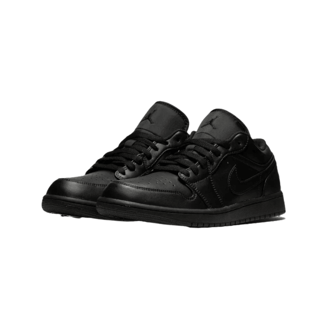 Elegante Nike Air Jordan 1 Low Triple Black sneakers op een groene achtergrond.