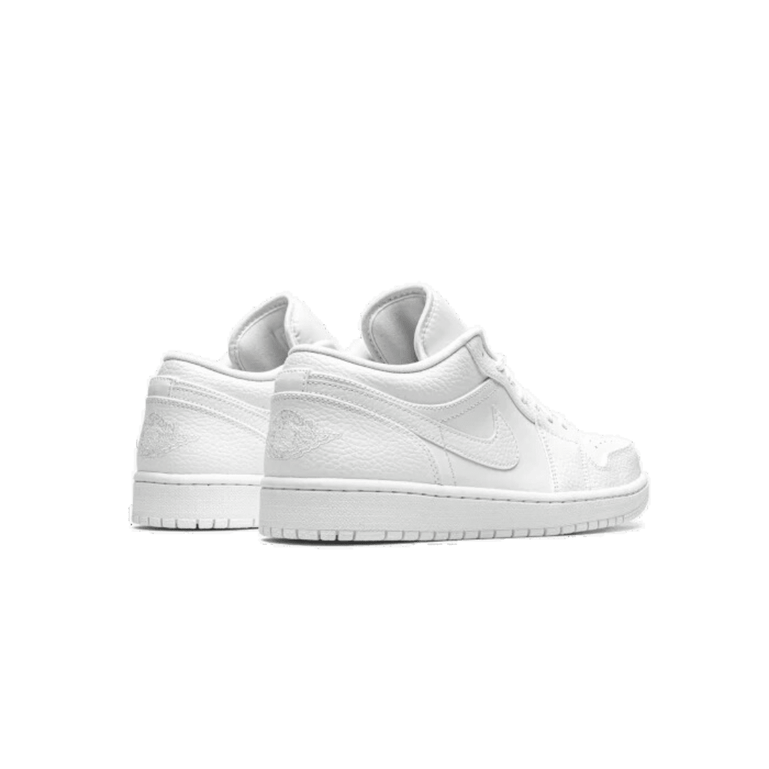 Witte Nike Air Jordan 1 Low sneakers op een effen groene achtergrond