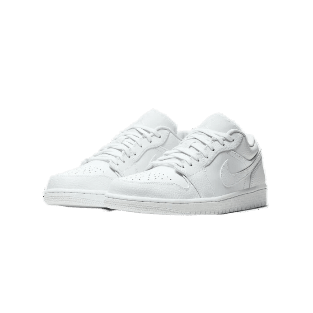 Glanzende witte Nike Air Jordan 1 Low sneakers tegen een groene achtergrond