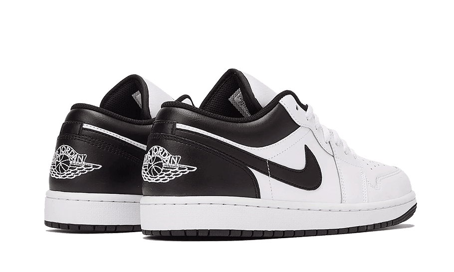 Klassieke zwart-witte Nike Air Jordan 1 Low sneakers tegen een groene achtergrond. De schoenen hebben een leren bovendeel met contrasterende zolen en accenten voor een stijlvol en sportief uiterlijk.