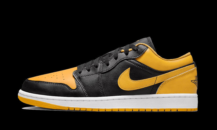 Zonnig paar Nike Air Jordan 1 Low sneakers in gele en zwarte kleuren, in het beeld tegen een groene achtergrond geplaatst.