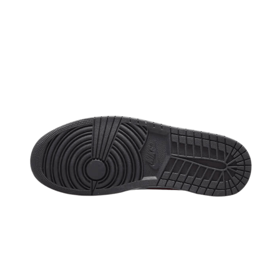 Zwarte Air Jordan 1 Mid Alternate Bred Toe sneakers op een groene achtergrond