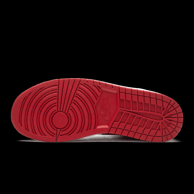 Rode Air Jordan 1 Mid Banned (2020) sneakers van Nike op een groene achtergrond. De sneakers hebben een klassieke Air Jordan 1-look met het kenmerkende Swoosh-logo en de opvallende rode kleur.