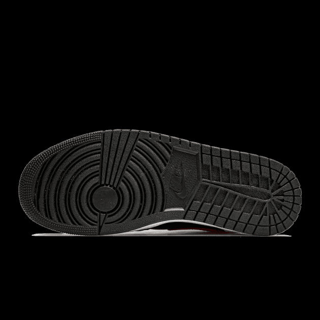 Zwarte Nike Air Jordan 1 Mid sneakers met rode en witte details tegen een groene achtergrond