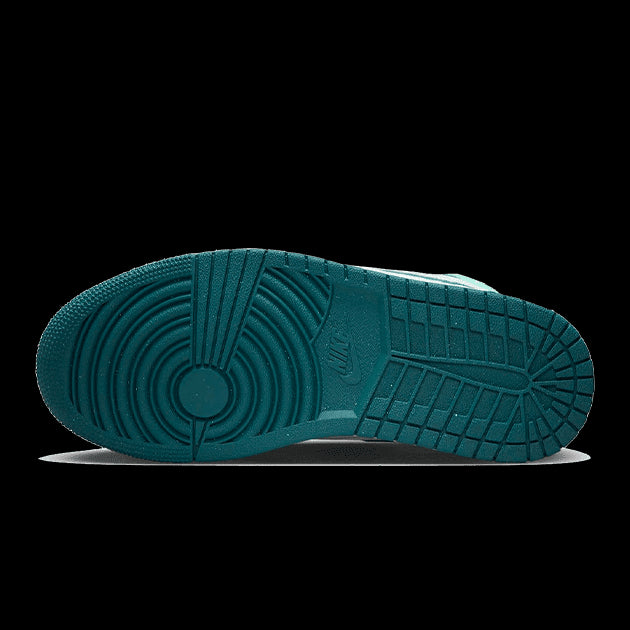 Turquoise Nike Air Jordan 1 Mid sneakers met een uniek gestructureerd zoolontwerp op een groene achtergrond