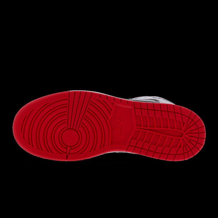 Rode Nike Air Jordan 1 Mid Cement sneakers op een groene achtergrond