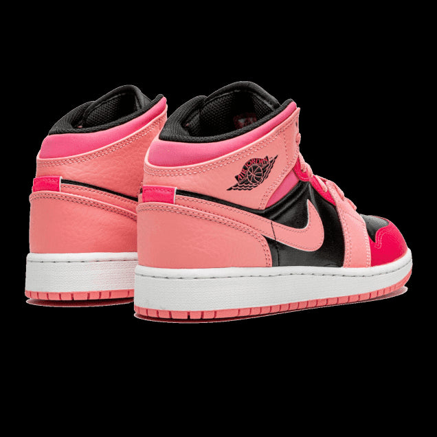 Roze en zwarte Nike Air Jordan 1 Mid Coral Chalk sneakers op een groene achtergrond